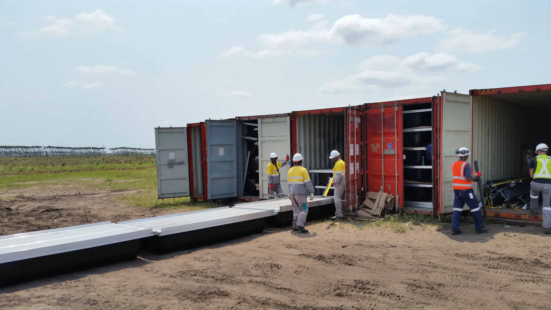 Crews unloading walkway sections from shipping containers